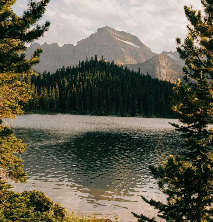 Lago tranquilo rodeado de pinos y montañas, evocando momentos inesperados y situaciones incómodas de la vida laboral.