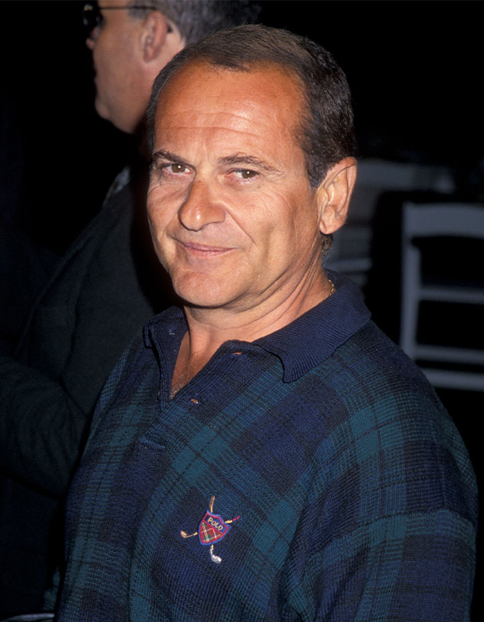 Estrella masculina sonriendo con camisa azul de cuadros en evento, relacionado con altura real de hombres famosos.