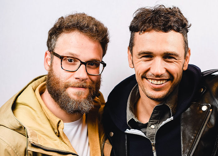 Dos amigos celebridades sonrientes, uno con gafas y barba, el otro con chaqueta de cuero, representando rupturas dramáticas de amistad.