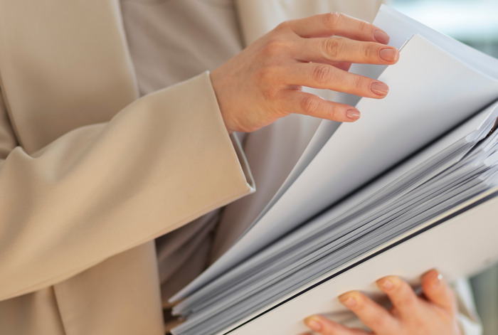 Persona revisando documentos en una carpeta gruesa, simbolizando momentos inesperados y situaciones incómodas en el trabajo.