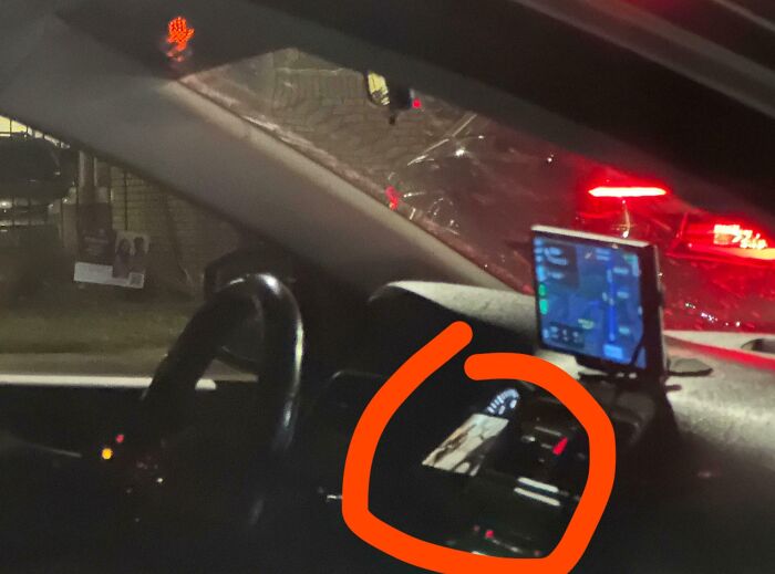 Interior de automóvil de noche con volante y dispositivo GPS, destacando acción expuesta de personas malintencionadas.