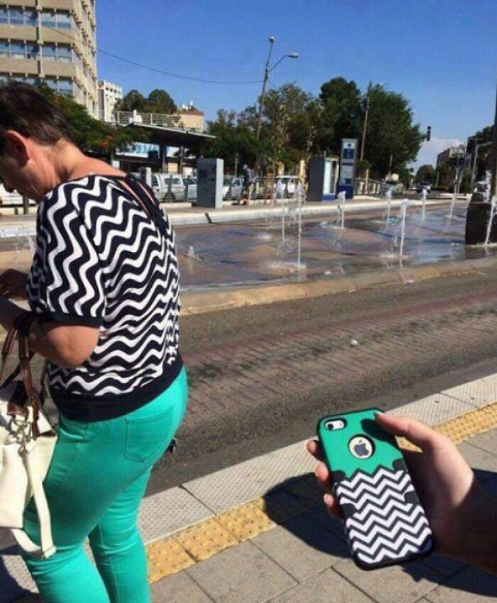 Mujer con blusa y funda de teléfono de zigzag en espacio público en foto de accidental comedy que provoca risa.