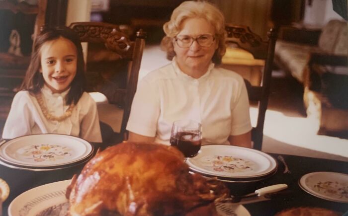 Niña y mujer mayor en mesa con pavo, foto familiar clásica de los 80s, momento fascinante de los años 80.
