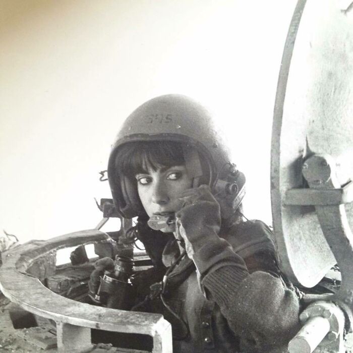 Mujer con casco y equipo militar en tanque, foto que refleja la energía salvaje y fascinante de los años 1980.