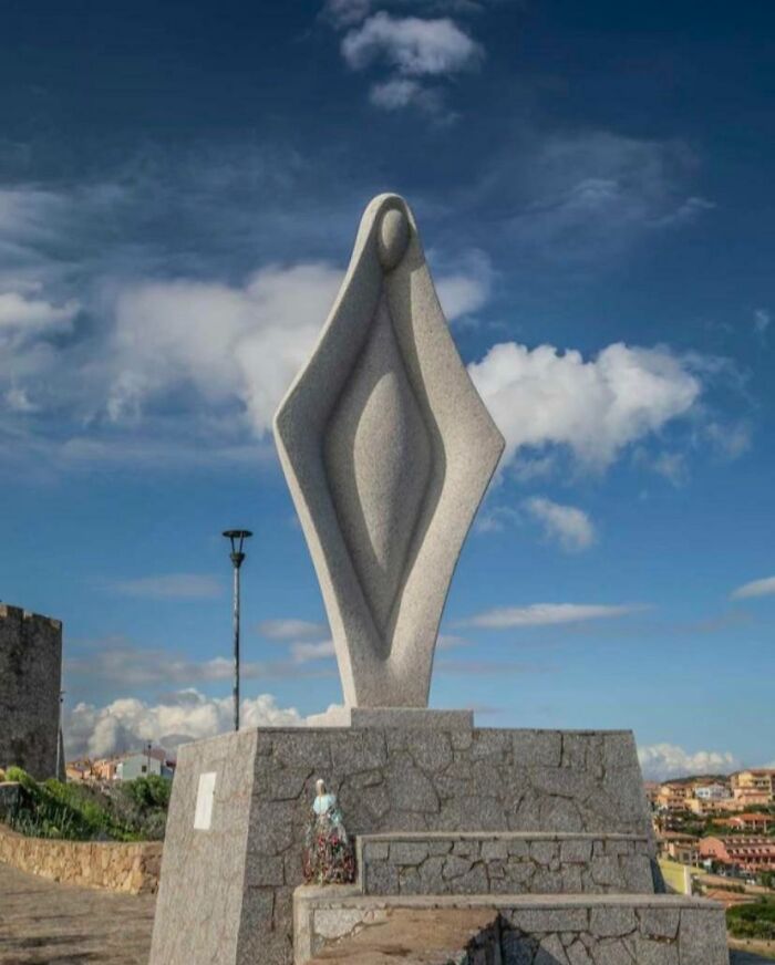 Escultura abstracta en piedra sobre base de cantera con cielo azul, con humor accidental y comedia en imagen divertida.