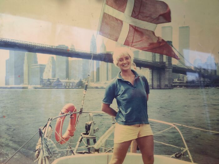 Mujer sonriente en velero frente al puente de Brooklyn en una foto fascinante de los años 1980 que muestra lo salvaje.