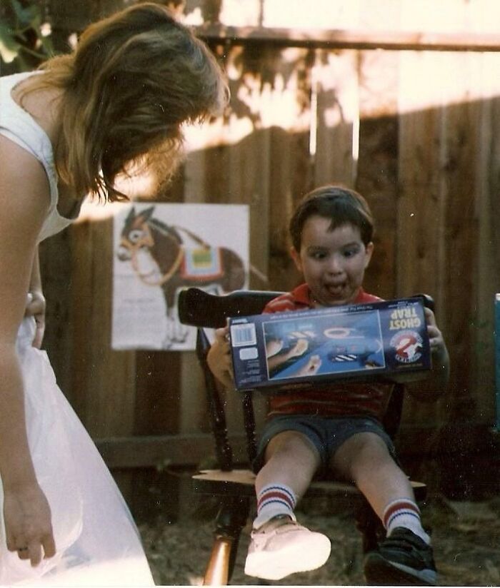 Niño emocionado con juguete Ghost Trap de Los Cazafantasmas en foto vintage que refleja la diversión de los años 1980.