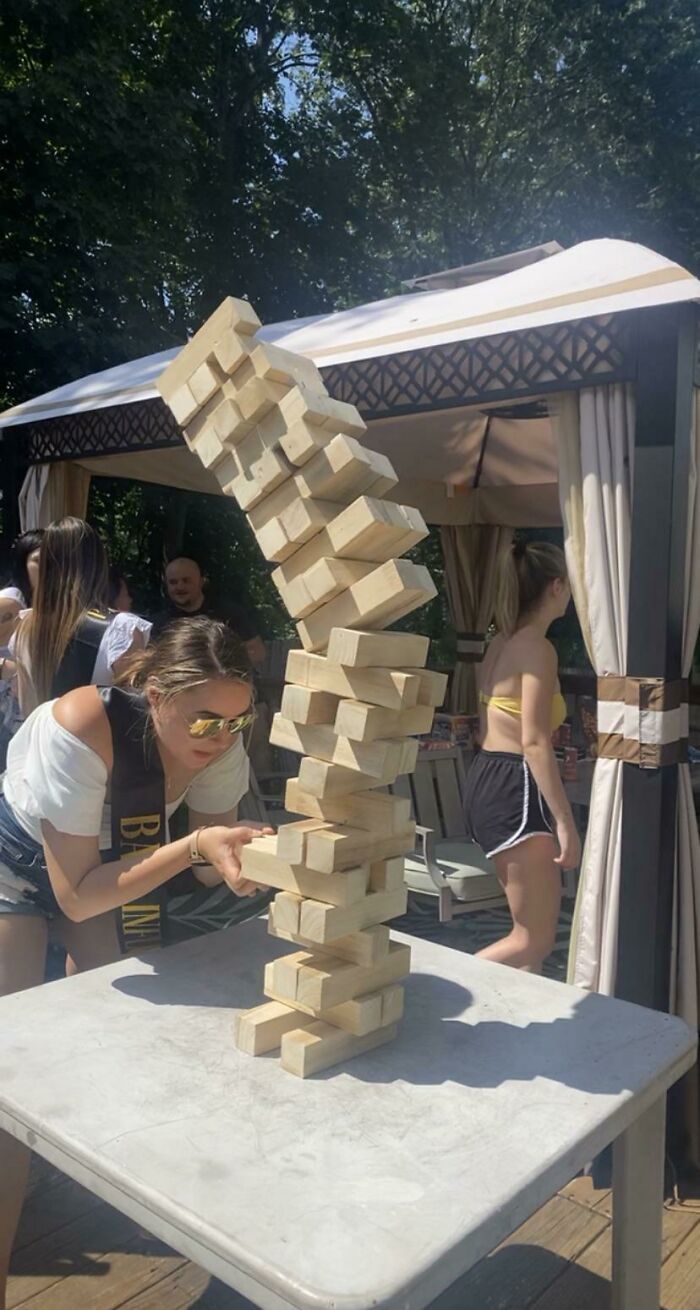 Mujer en juego de jenga capturando el momento antes de un desastre con torre de bloques a punto de caer.