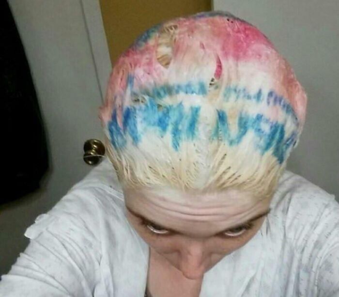 Persona con accidente de cabello tragicómico con decoloración y colores azul y rosa en la cabeza visible desde arriba.