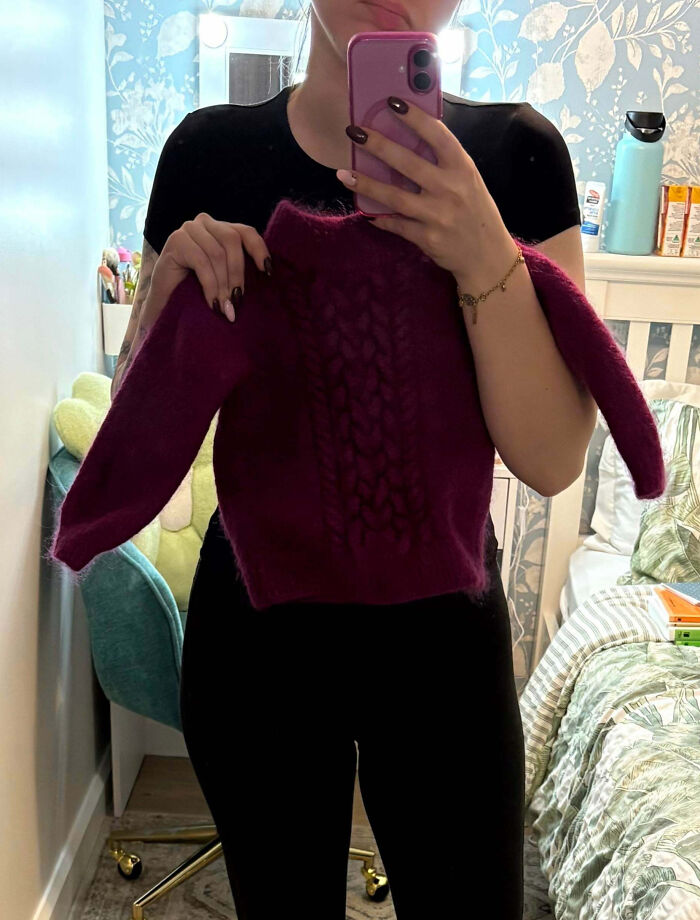 Persona sosteniendo un suéter pequeño color púrpura frente a un espejo en un dormitorio, mostrando que siempre puede empeorar.