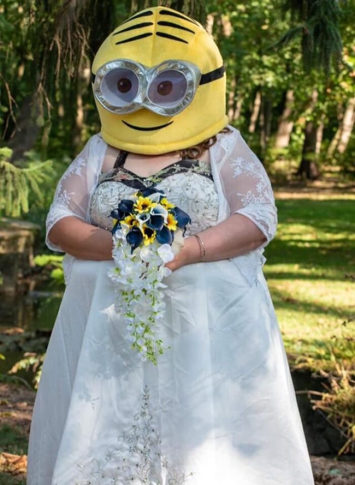 Novia con vestido de boda sosteniendo ramo, con disfraz gigante de Minion, ejemplo de errores al comprar vestido.