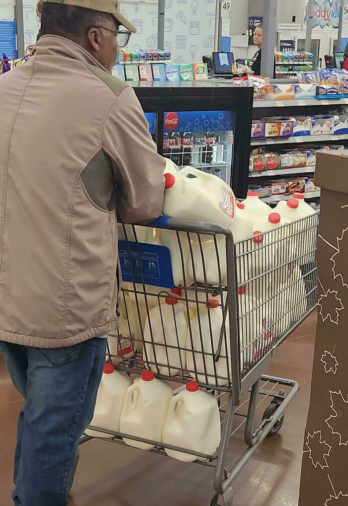 Hombre empujando carrito lleno de galones de leche en Walmart, foto divertida y confusa de People Of Walmart.