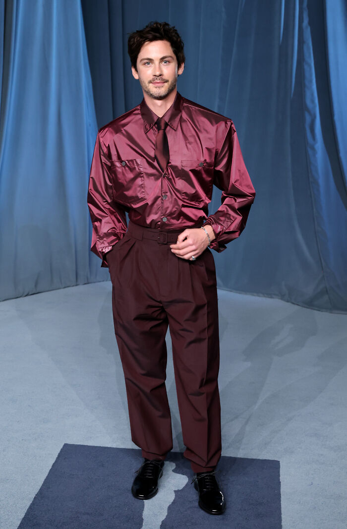 Hombre con camisa satinada y pantalones burdeos posando en gala del museo de la academia moda 2025. Hombre con camisa satinada y pantalones burdeos posando en gala del museo de la academia moda 2025.