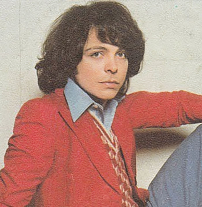 Joven con chaqueta roja sentado, relacionado con figuras públicas desaparecidas sin dejar rastro en la cultura popular.