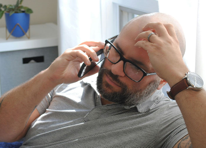 Hombre preocupado hablando por teléfono sobre caos y engaños que surgen en la sala de partos tras descubrir la verdad.