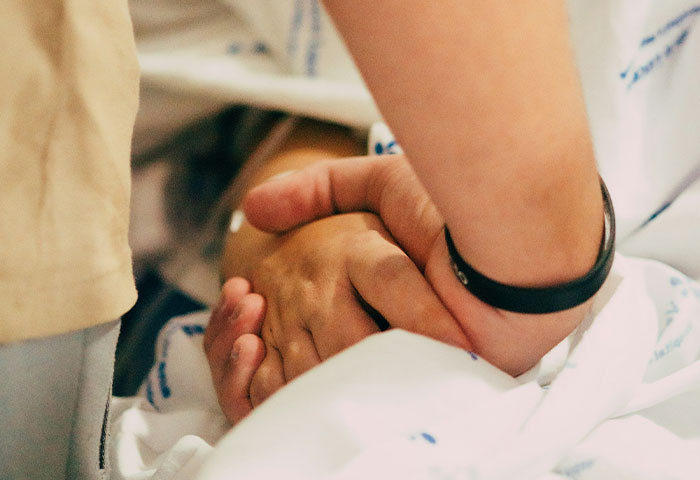 Manos entrelazadas en sala de parto representando caos tras descubrir infidelidad, momento de tensión y emociones fuertes.