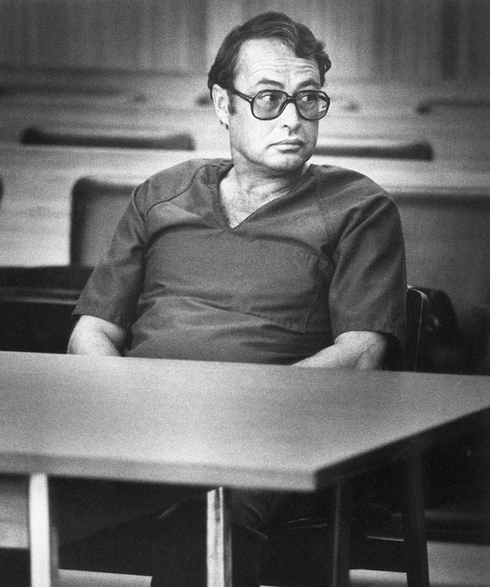 Hombre con gafas grandes y camiseta oscura sentado en sala vacía, representando figuras públicas desaparecidas sin rastro.