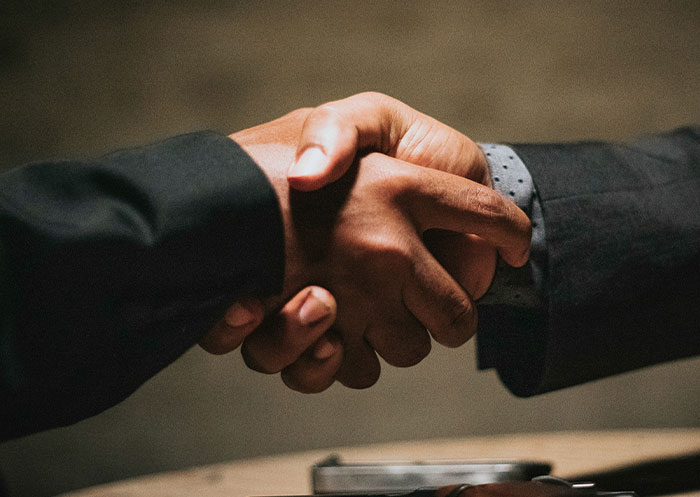 Dos personas dándose la mano en un encuentro formal, mostrando señales sociales malinterpretadas y momentos de cringe legendario.