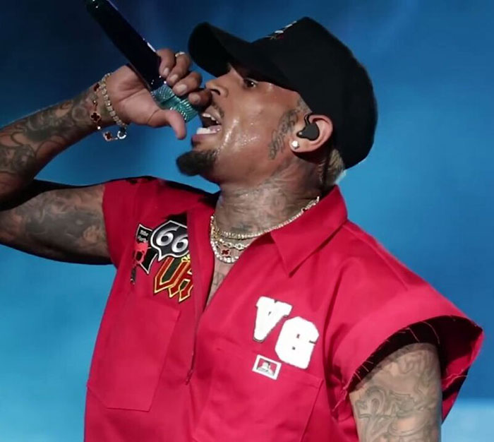 Cantante con gorra negra y camisa roja actuando en vivo, relacionado con celebridades que se negaron a jugar baloncesto en silla de ruedas. Cantante con gorra negra y camisa roja actuando en vivo, relacionado con celebridades que se negaron a jugar baloncesto en silla de ruedas.