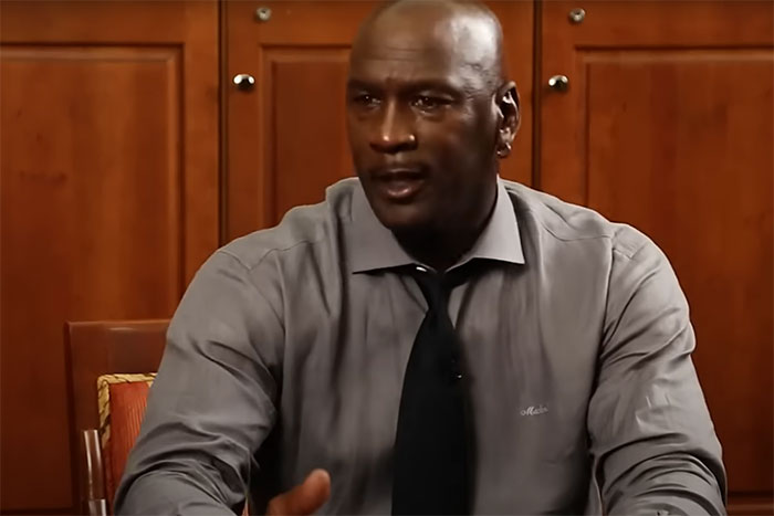 Hombre con camisa gris y corbata negra sentado en entrevista hablando sobre celebridades y basketball en silla de ruedas. Hombre con camisa gris y corbata negra sentado en entrevista hablando sobre celebridades y basketball en silla de ruedas.