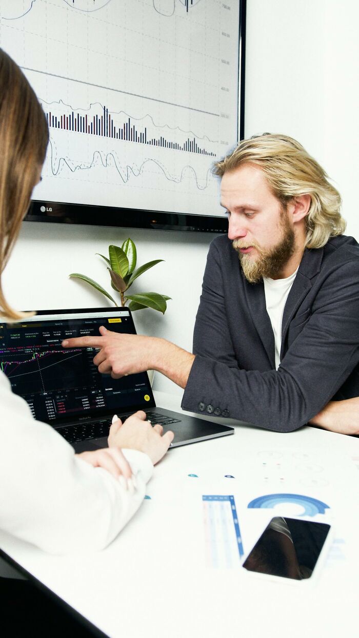 Hombre explicando gráficos financieros en laptop durante reunión sobre karma y consecuencias instantáneas en personas. Hombre explicando gráficos financieros en laptop durante reunión sobre karma y consecuencias instantáneas en personas.