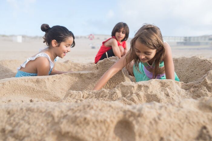 Niños jugando en la playa mientras están enterrados en la arena, mostrando momentos de karma instantánea y diversión. Niños jugando en la playa mientras están enterrados en la arena, mostrando momentos de karma instantánea y diversión.
