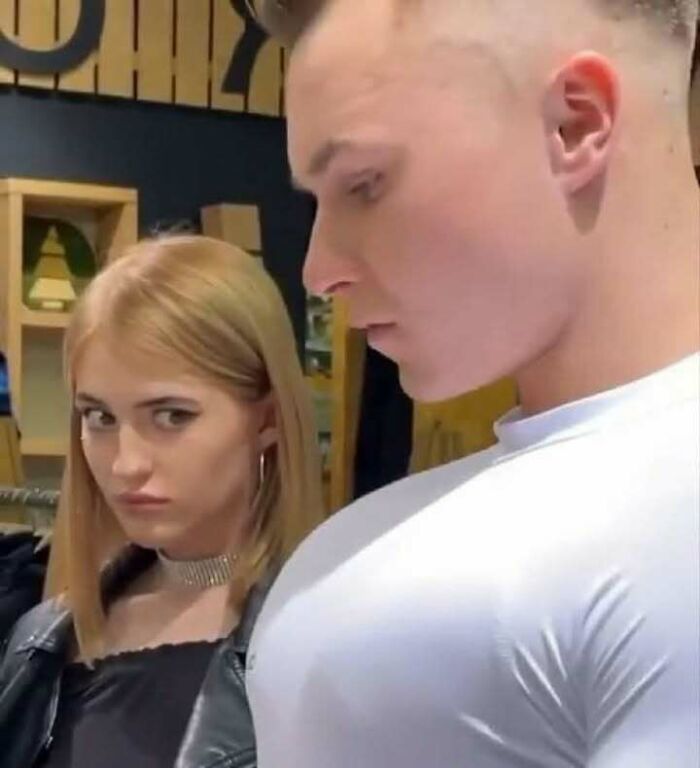 Hombre con camiseta ajustada y mujer mirando de reojo en escena graciosa de memes divertidos y random.