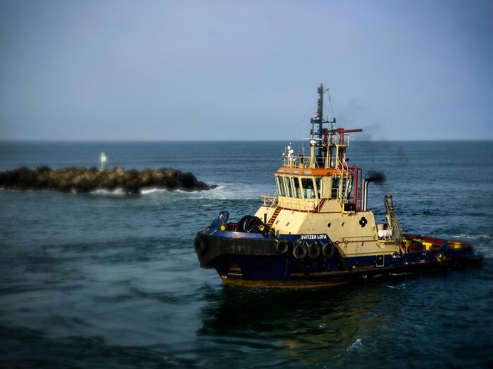 Barco remolcador en el mar cerca de un rompeolas, imagen que evoca piezas escalofriantes de metraje encontrado.