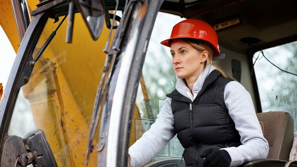 Mujer con casco de seguridad operando maquinaria, mostrando el estado distu00f3pico actual del mundo en la construcciu00f3n.