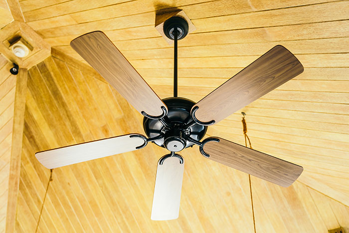 Ventilador de techo de madera instalado en techo con paneles, ilustrando consecuencias inesperadas de mentiras para otras personas.