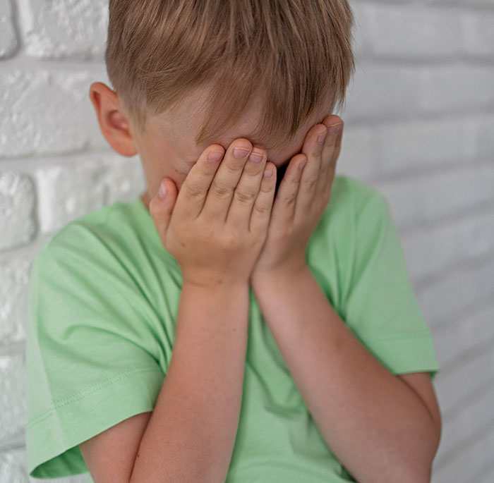 Niño cubriéndose el rostro con las manos mostrando las consecuencias de mentir y el impacto en otras personas.