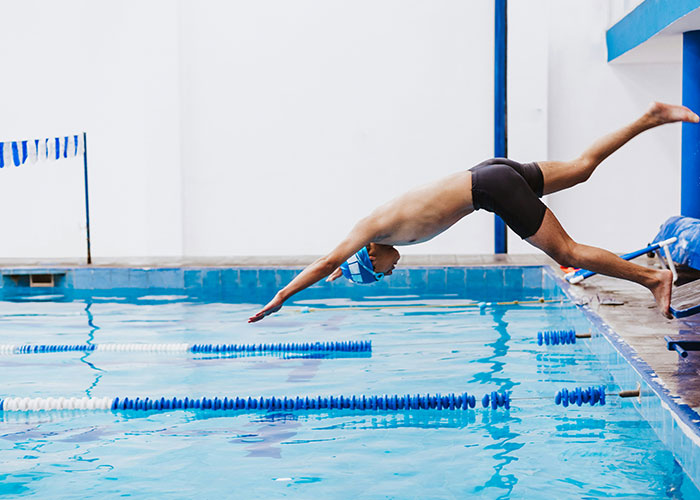 Joven nadador realizando clavado en piscina deportiva relacionado con hallazgos sorprendentes en autopsias. Joven nadador realizando clavado en piscina deportiva relacionado con hallazgos sorprendentes en autopsias.