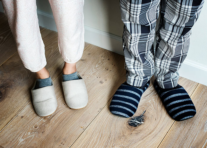 Pies de dos personas con pantuflas sobre suelo de madera en casa, coincidencia con palabras clave de autopsia y hallazgos médico forenses. Pies de dos personas con pantuflas sobre suelo de madera en casa, coincidencia con palabras clave de autopsia y hallazgos médico forenses.