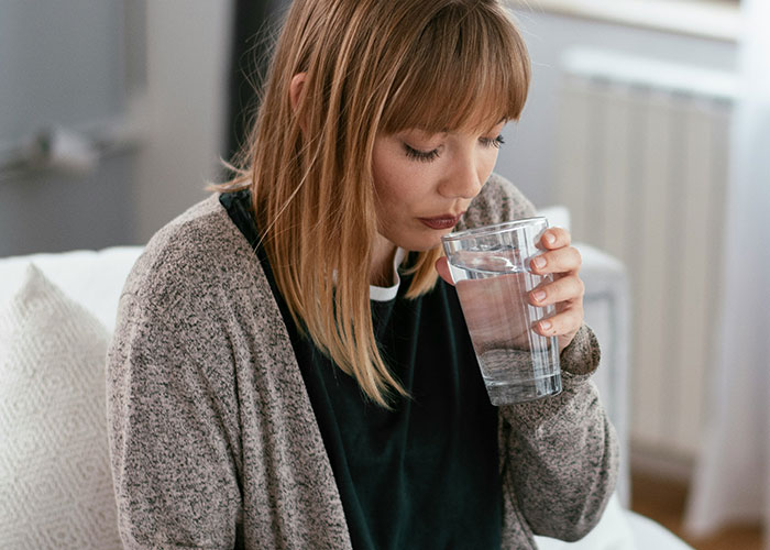 Mujer pensando profundamente y bebiendo agua en casa, relacionada con hallazgos sorprendentes de médicos forenses. Mujer pensando profundamente y bebiendo agua en casa, relacionada con hallazgos sorprendentes de médicos forenses.