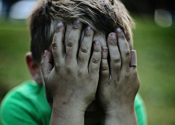 Niño con las manos sucias cubriéndose el rostro, simbolizando momentos de karma instantáneo y justicia merecida.