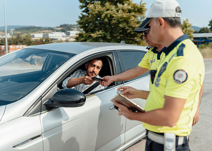 Hombre entregando licencia a policía en control de tráfico, momento de karma instantáneo donde recibe lo que merece.