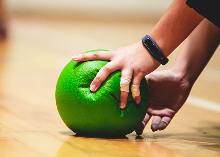 Mano vendada sosteniendo bola de entrenamiento verde, representando momentos de karma instantáneo donde la gente recibió lo que merecía.