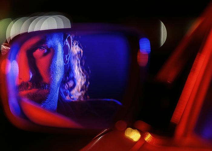 Hombre con expresión seria reflejado en espejo retrovisor, momentos de karma instantáneo y consecuencias justas.