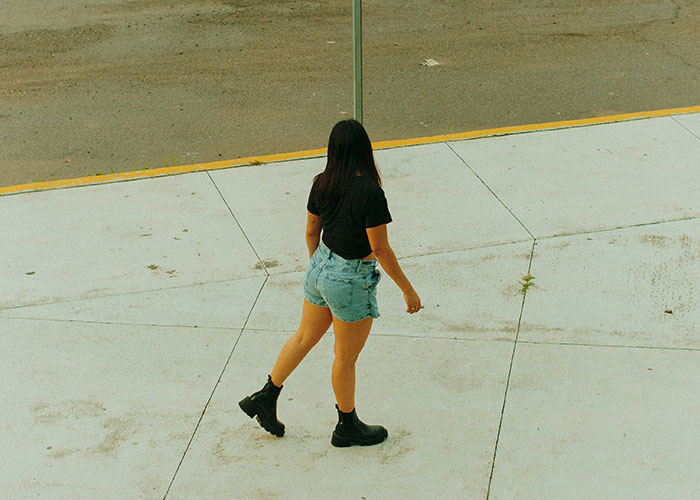 Mujer con botas negras y shorts caminando en la calle, ilustrando momentos de karma instantáneo y justicia inmediata.