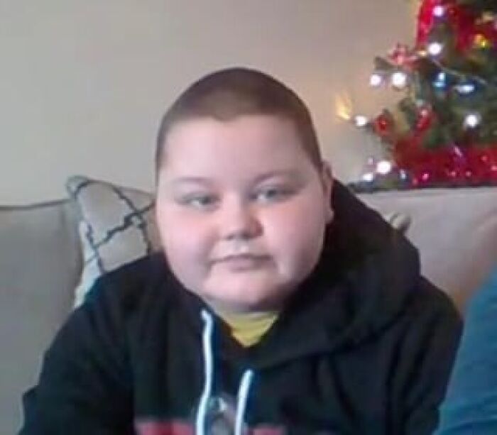 Niño con sudadera negra sentado en sofá frente a árbol decorado, imagen relacionada con publicaciones médicas impactantes en línea.