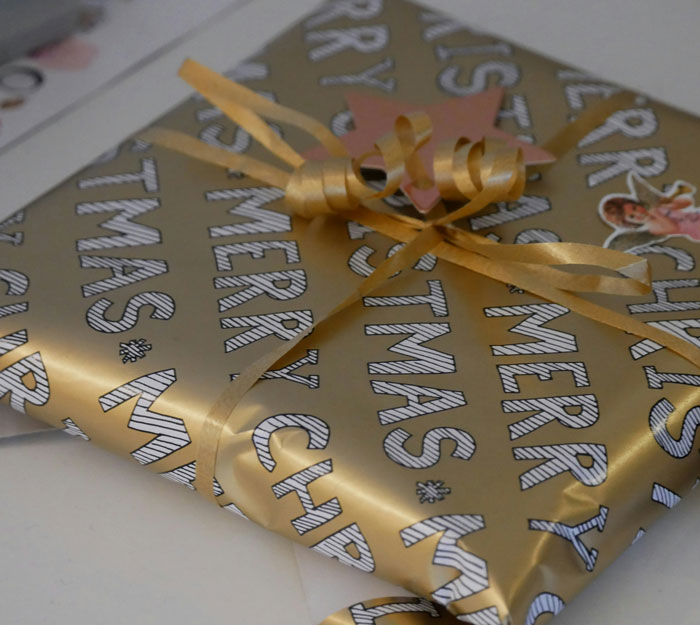 Regalo envuelto en papel dorado navideño con lazo para historias de drama familiar divertidas y caóticas.