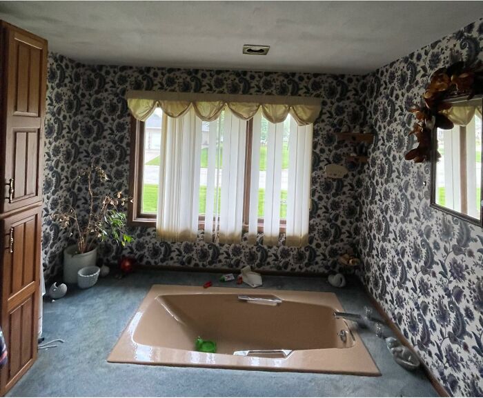 Baño con bañera empotrada y papel tapiz anticuado, ejemplo de anuncios de Zillow tan malos que parecen falsos.
