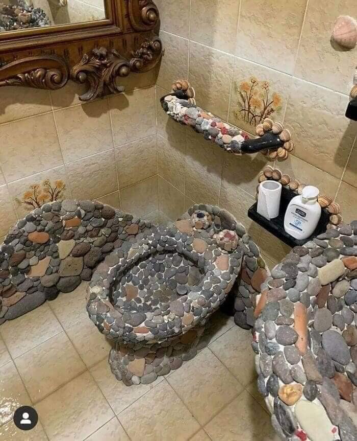 Baño con inodoro y lavamanos cubiertos de piedras decorativas, diseño extraño en listado Zillow tan malo que parece falso.