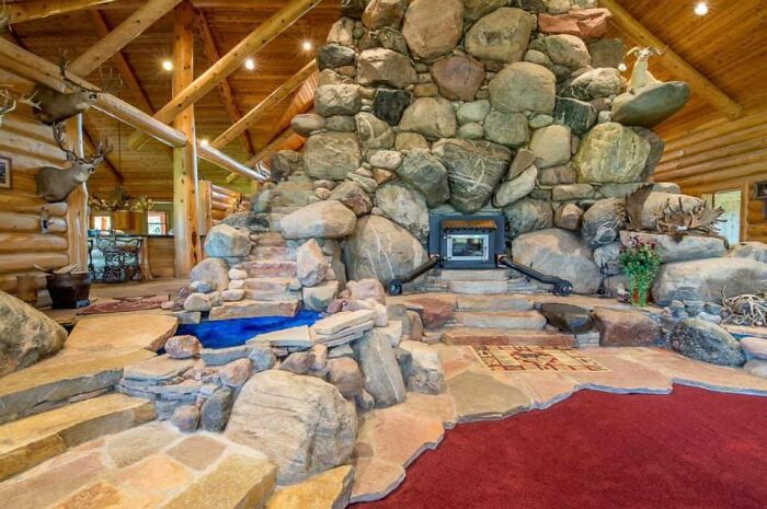 Chimenea gigante de piedra en casa tipo cabaña con decoración rústica y muebles de madera vista interior extraña en Zillow.