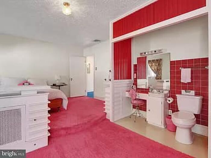 Habitación con alfombra rosa y baño integrado con decoración y azulejos rojos en listado de Zillow impactante y falso.