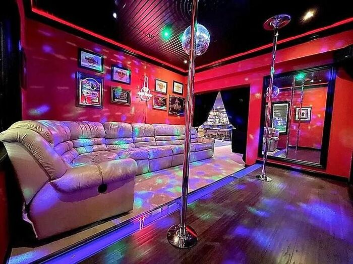 Sala con sofá en forma de L, barras de pole dance y luces de discoteca, ejemplo de listados Zillow malos y falsos.