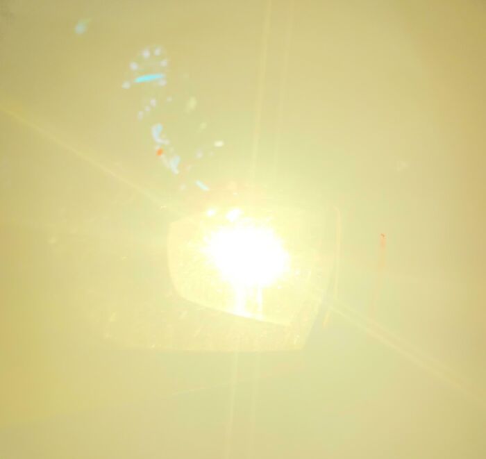 Reflejo del sol en espejo retrovisor de auto, ilustrando falta de sentido común y situaciones sorprendentes.