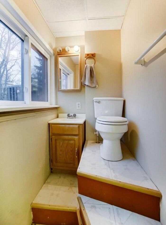 Baño pequeño con inodoro y lavabo en plataforma elevada, ejemplo de listados Zillow tan malos que parecen falsos.