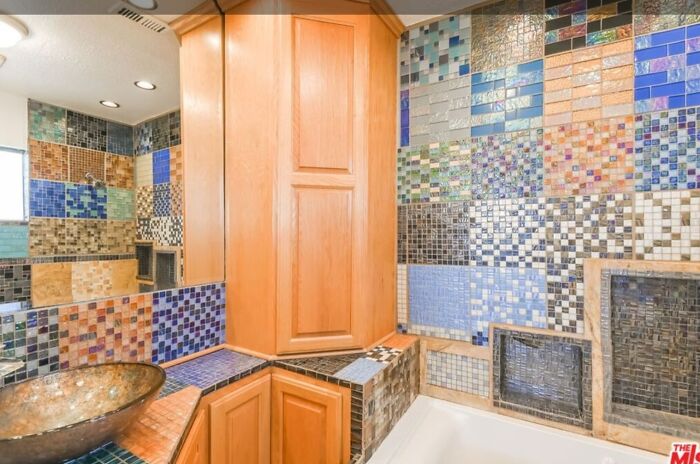 Baño con azulejos de colores variados y lavabo de cobre en una de las peores listas de Zillow que parecen falsas.