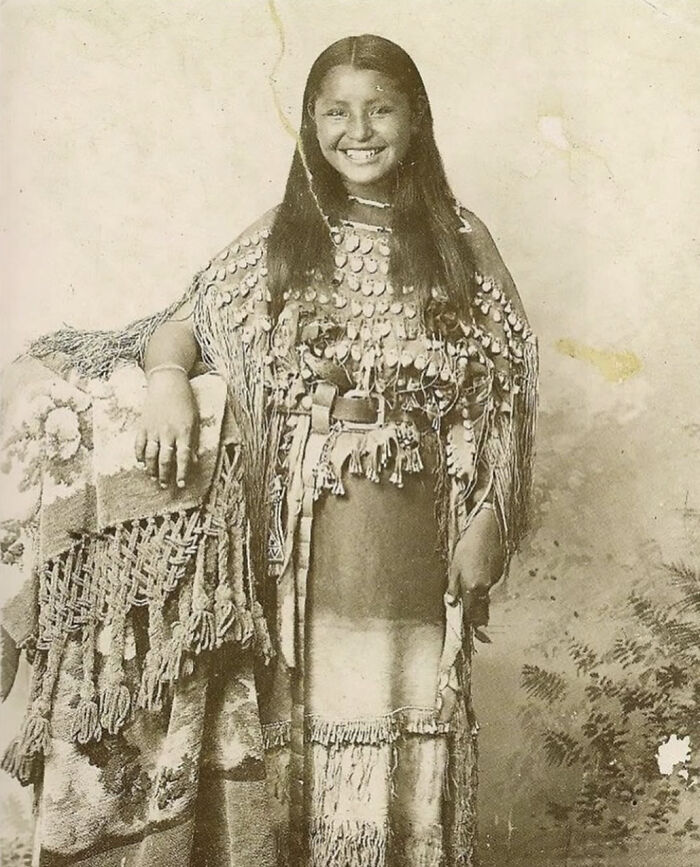 Joven indígena en vestido tradicional posando para foto rara y poderosa de comunidad histórica online destacada.